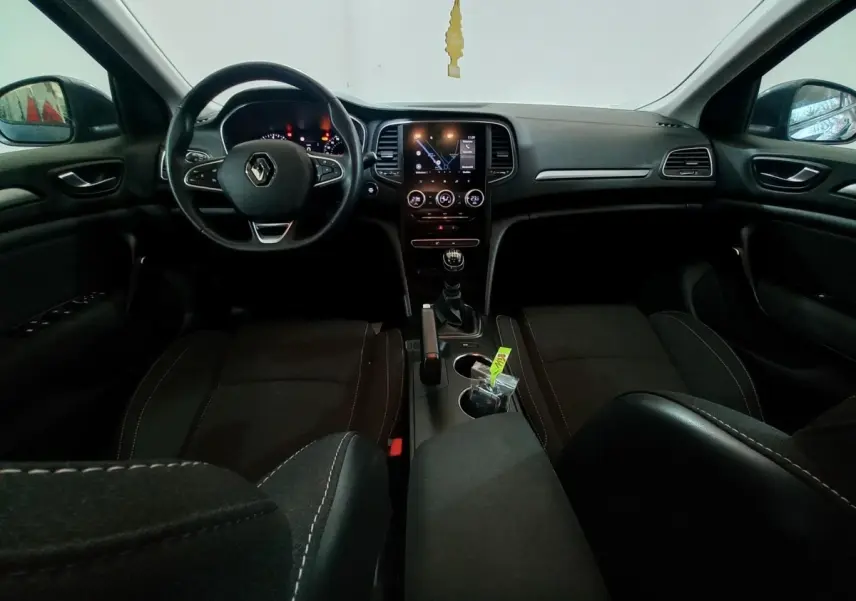 Vue intérieure avant de la Renault Mégane Business TCe 115, tableau de bord noir avec écran tactile central et volant multifonctions.