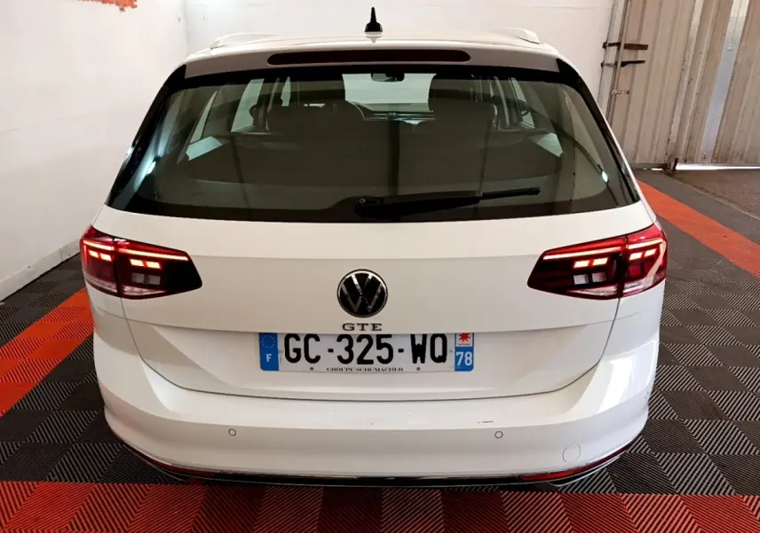Vue arrière d'une Volkswagen Passat GTE blanche avec feux LED allumés et plaques d'immatriculation françaises.