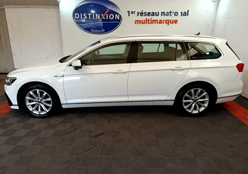 Volkswagen Passat break blanc vue de profil côté gauche, intérieur visible à travers les vitres teintées.