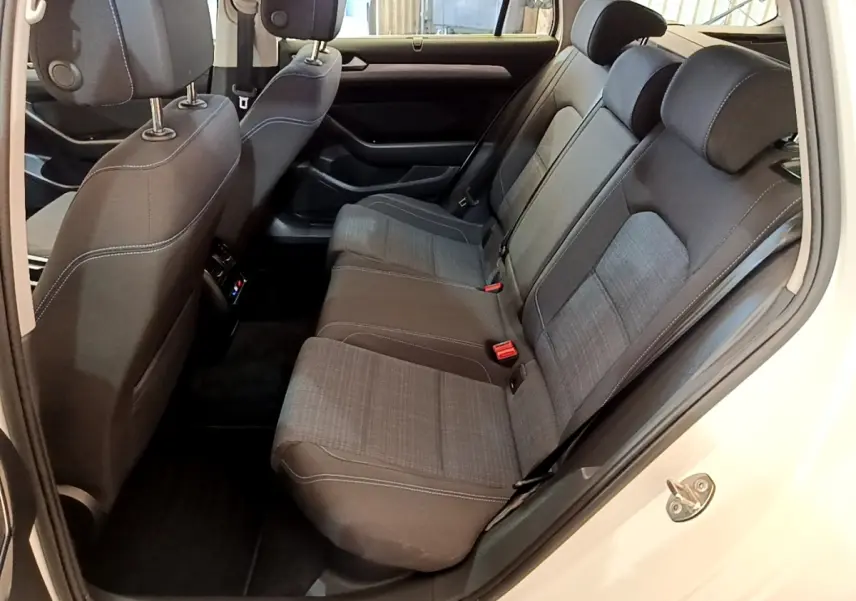 Vue intérieure côté droit des sièges arrière gris foncé avec surpiqûres blanches de la Volkswagen Passat hybride rechargeable blanche.