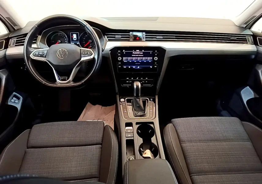 Vue intérieure avant de la Volkswagen Passat GTE 2021, tableau de bord noir avec écran tactile central et volant multifonctions.