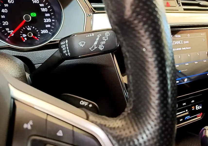 Gros plan intérieur sur le volant cuir noir et la commande d’essuie-glace de la Volkswagen Passat hybride blanche de 2021.