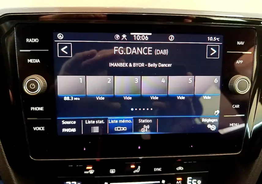 Écran tactile central affichant la radio digitale dans un Volkswagen Passat blanc, vue intérieure frontale.