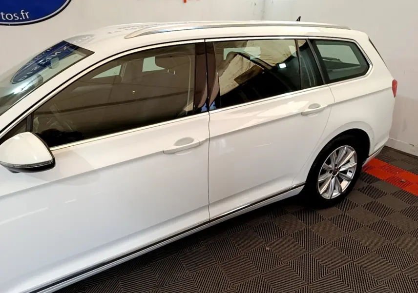 Vue de profil côté gauche d'une Volkswagen Passat break hybride blanche avec jantes alliage et vitres teintées.