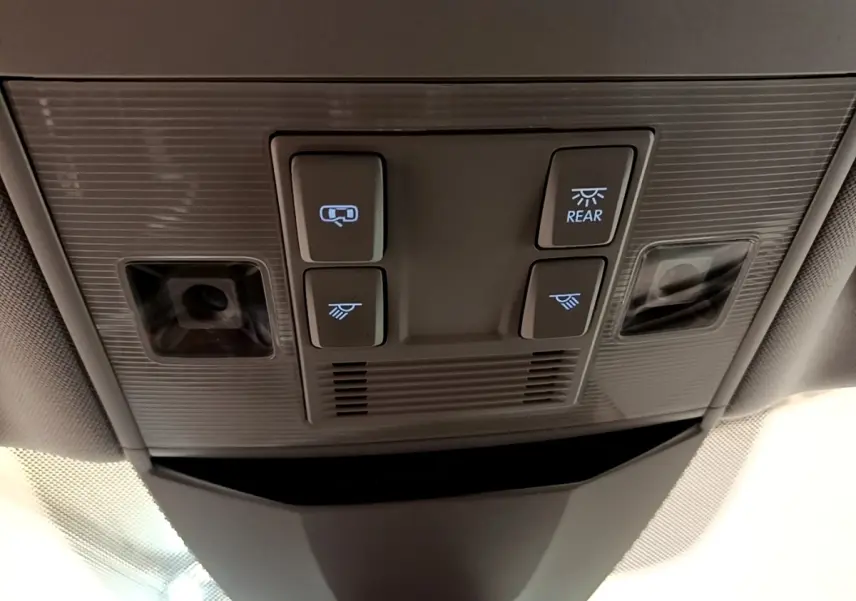 Vue en gros plan du plafonnier gris avec commandes d'éclairage et capteurs dans une Volkswagen Passat blanche hybride 2021.