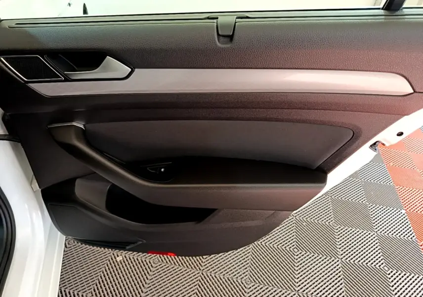 Vue rapprochée de la porte avant gauche blanche de la Volkswagen Passat 2021 avec garniture noire et insert décoratif gris.