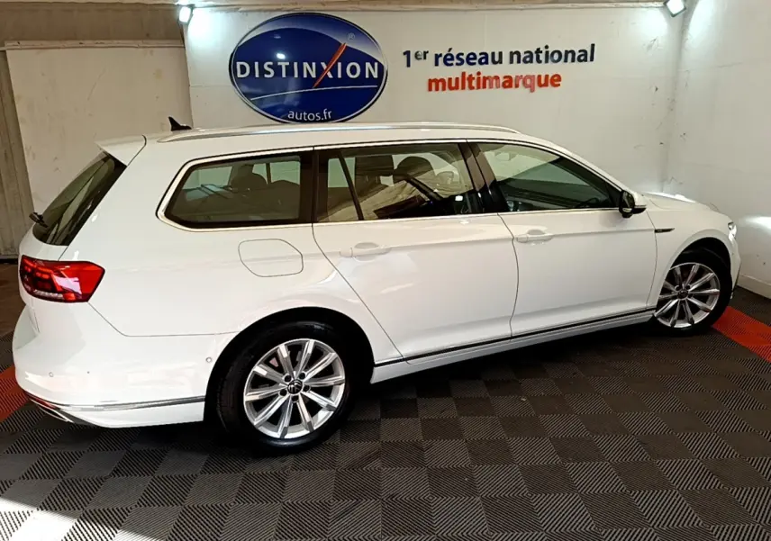 Volkswagen Passat break blanc vue de profil côté gauche dans un showroom avec logo Distinxion en arrière-plan.