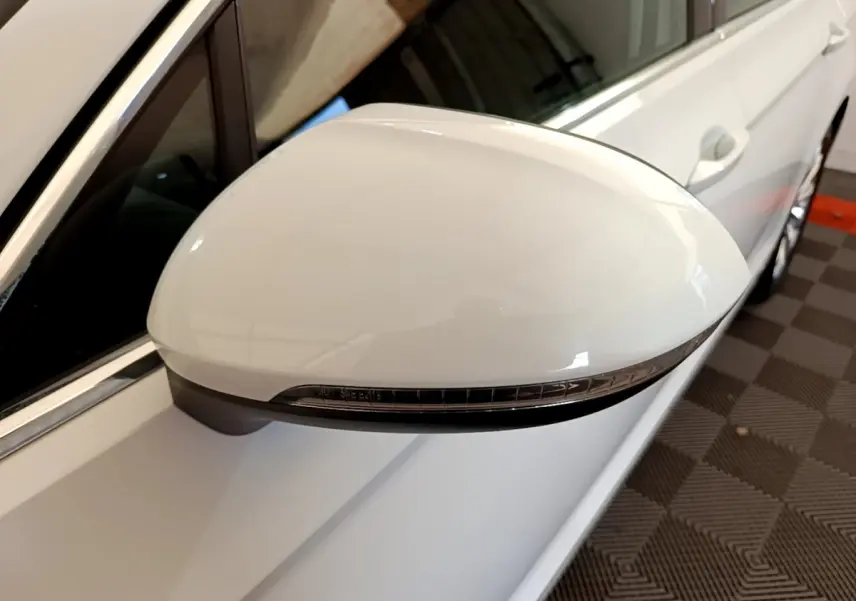 Rétroviseur blanc côté gauche de la Volkswagen Passat hybride 2021, avec clignotant intégré, vue rapprochée en intérieur.