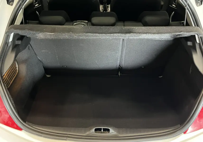 Coffre ouvert d'une Peugeot 208 blanche de 2014, vue arrière montrant l'espace de chargement et la banquette arrière noire.