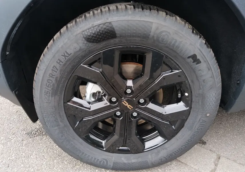 Gros plan sur la roue avant droite du Dacia Duster Hybrid-G 150 ch, jante noire brillante avec logo Dacia central.