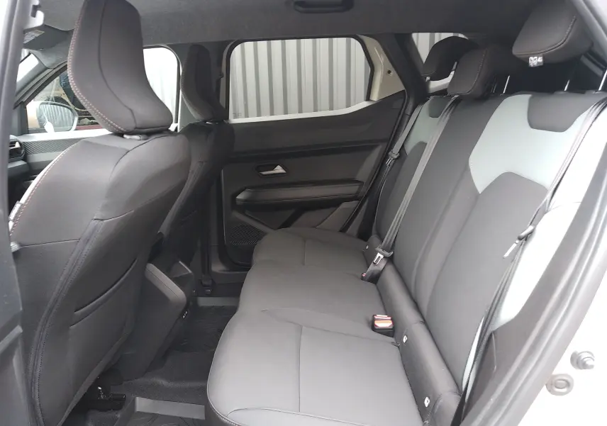 Vue intérieure côté droit des sièges arrière noirs avec appuie-têtes du Dacia Duster Hybrid-G 2026 en version Spirit of Sand.