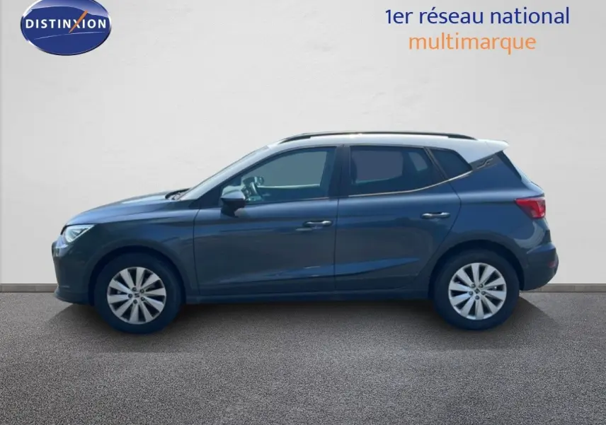 Vue de profil côté gauche d’un SEAT Arona gris Magnetic Metal avec toit noir, en arrière-plan un mur blanc.