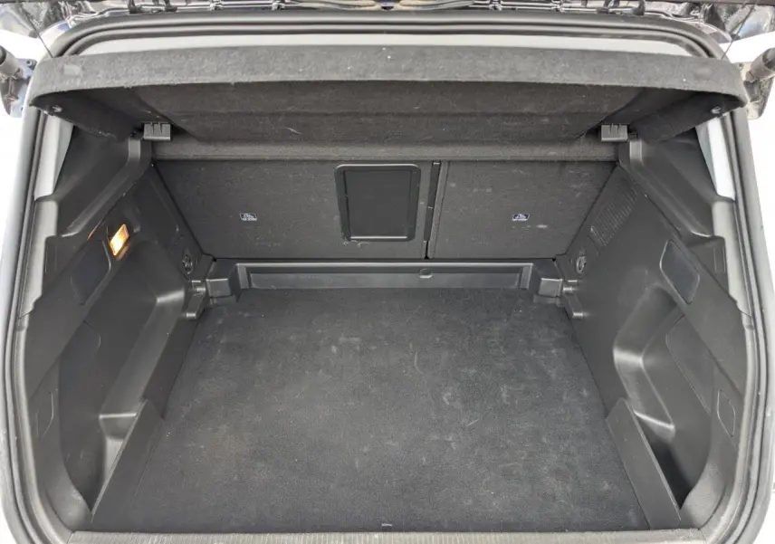 Coffre ouvert vu de l'arrière d'un Opel Grandland blanc métallisé, espace de chargement vide et tapis noir.