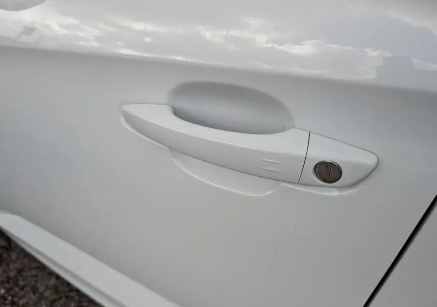 Poignée de porte blanche métallisée côté gauche de l'Opel Grandland 2024 avec serrure intégrée.