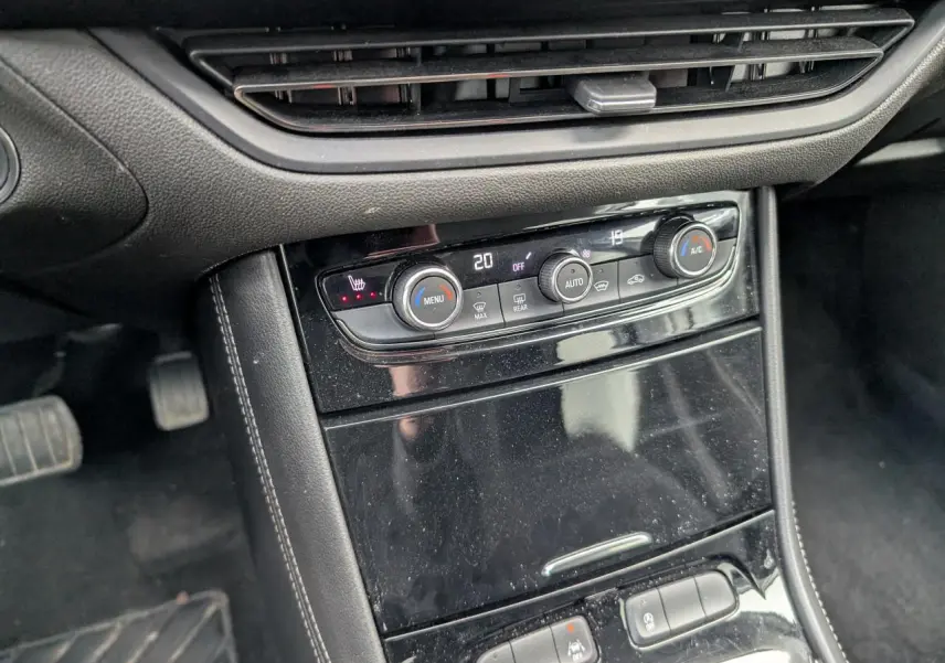 Vue rapprochée de la console centrale noire brillante avec commandes de climatisation et boutons multifonctions de l'Opel Grandland 2024.