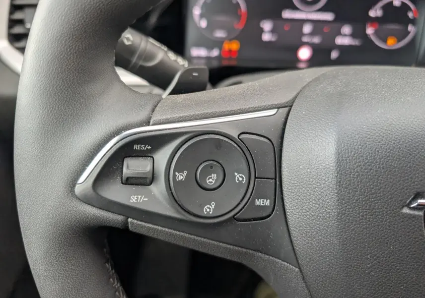 Gros plan sur les commandes de régulateur de vitesse et chauffage du volant sur le côté gauche du volant noir d’un Opel Grandland.