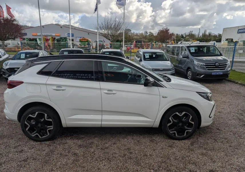 Opel Grandland blanc métallisé vu de profil côté gauche avec toit noir et jantes alliage noires.