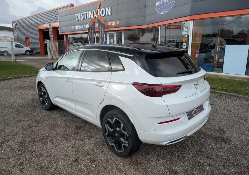 Opel Grandland blanc métallisé vue 3/4 arrière droit avec toit noir et jantes alliage noires.