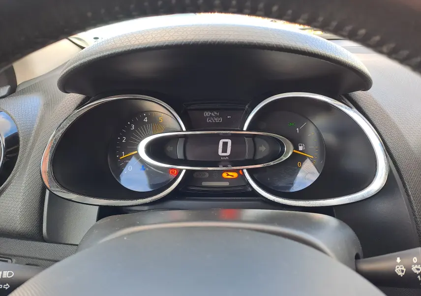 Vue rapprochée du tableau de bord de la Renault Clio IV, affichage digital au centre avec compte-tours et jauge à carburant.
