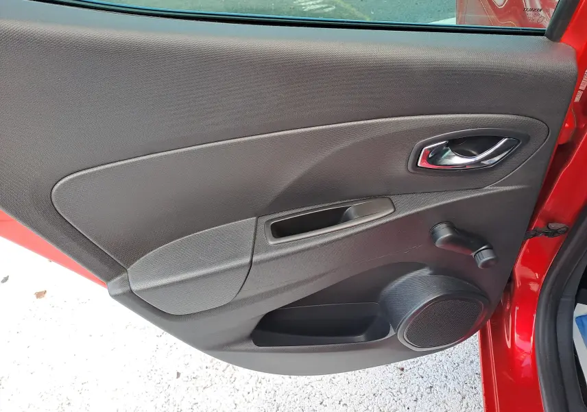 Vue intérieure de la porte arrière gauche rouge d'une Renault Clio IV 1.5 DCI 75 Limited avec commande manuelle de vitre.