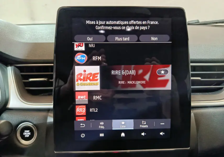Écran tactile central du tableau de bord du Renault Captur rouge 2024 affichant les stations radio avec bouton démarrage visible à gauche.