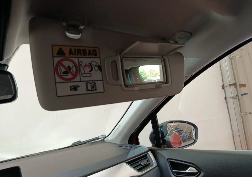 Vue intérieure côté conducteur du pare-soleil avec miroir et rétroviseur extérieur d’un Renault Captur rouge 2024.