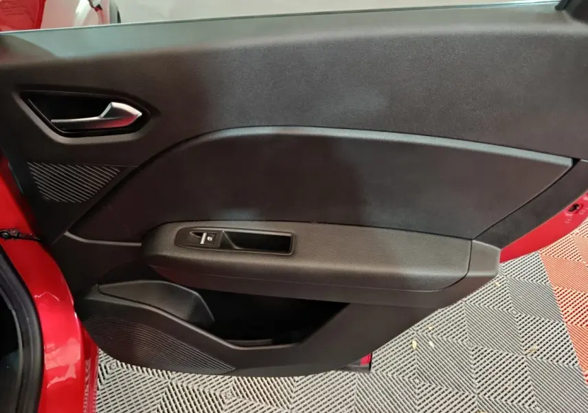 Vue intérieure côté gauche de la porte avant rouge du Renault Captur 2024 avec poignée et commande de vitre noire.