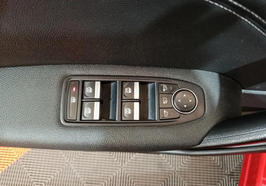 Commande des vitres et rétroviseurs sur la porte côté conducteur d’un Renault Captur rouge 2024, vue en plongée.