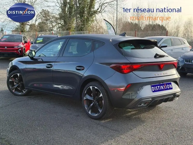 Vue 3/4 arrière droite d'une SEAT LEON 1.5 eTSI Hybrid Business 2025 en gris magnétique métallisé, avec jantes distinctives.