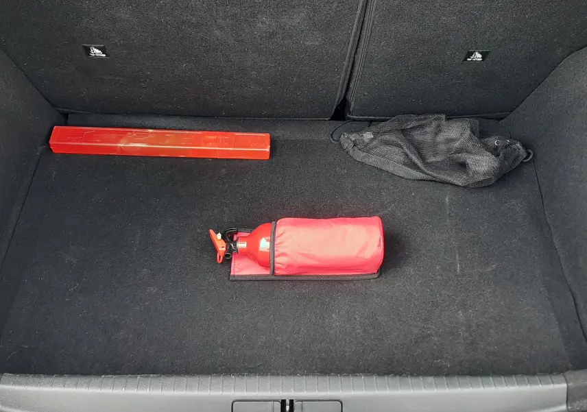 Coffre ouvert d'une Peugeot 208 gris Artense, vue de dessus, avec extincteur rouge et triangle de signalisation.