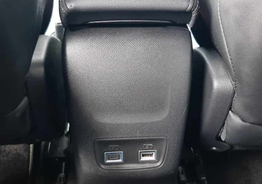 Prise USB-C et USB-A sur la console centrale arrière en cuir noir du Peugeot 208 GT 2025, vue rapprochée.