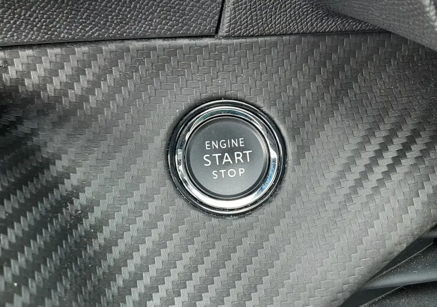 Bouton start/stop moteur sur tableau de bord effet carbone de la Peugeot 208 1.2 100CH S&S GT, intérieur noir.