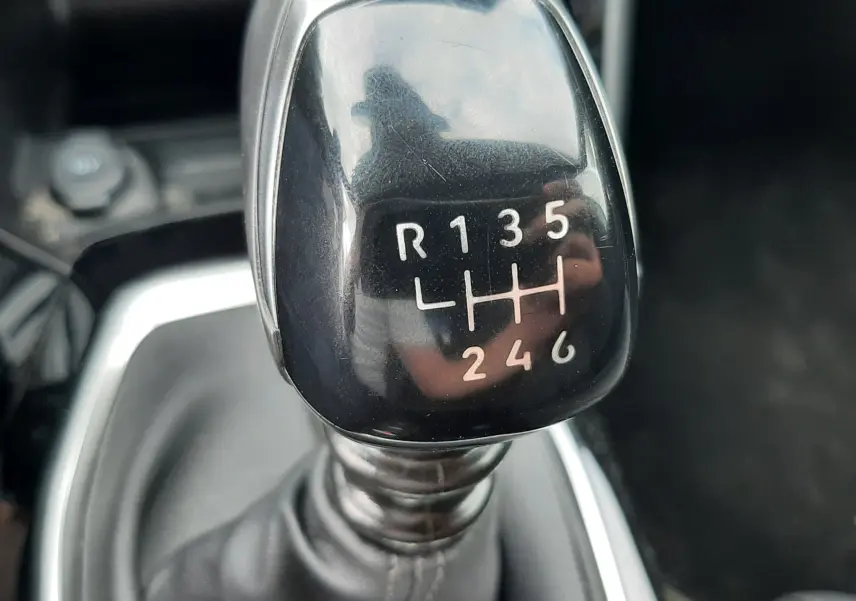 Gros plan sur le levier de vitesses manuel noir brillant de la Peugeot 208 1.2 100CH S&S GT, intérieur gris.