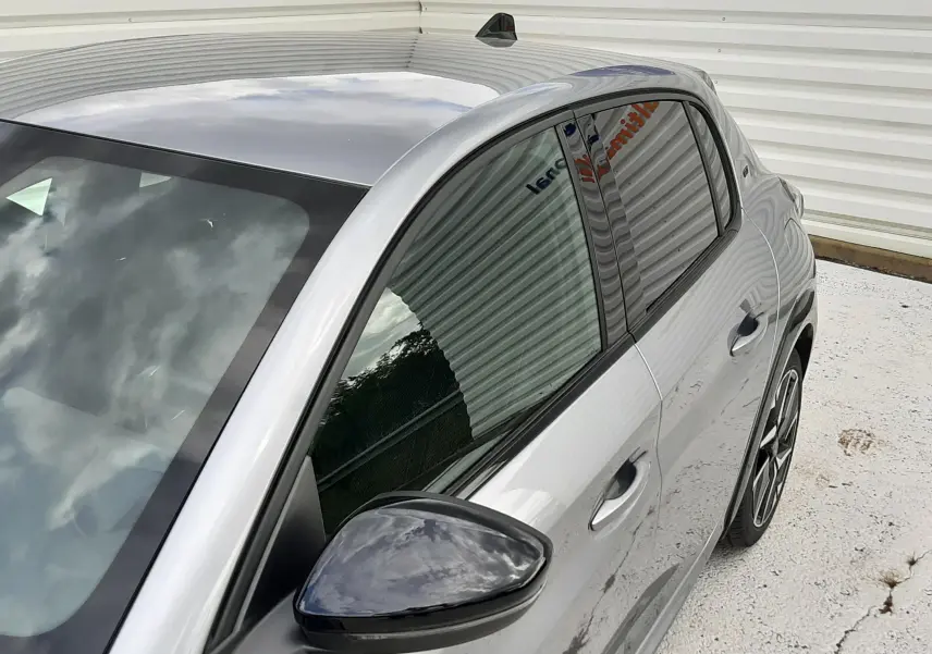 Vue de trois quarts avant droit d'une Peugeot 208 GT gris Artense avec rétroviseur noir et jantes alliage.