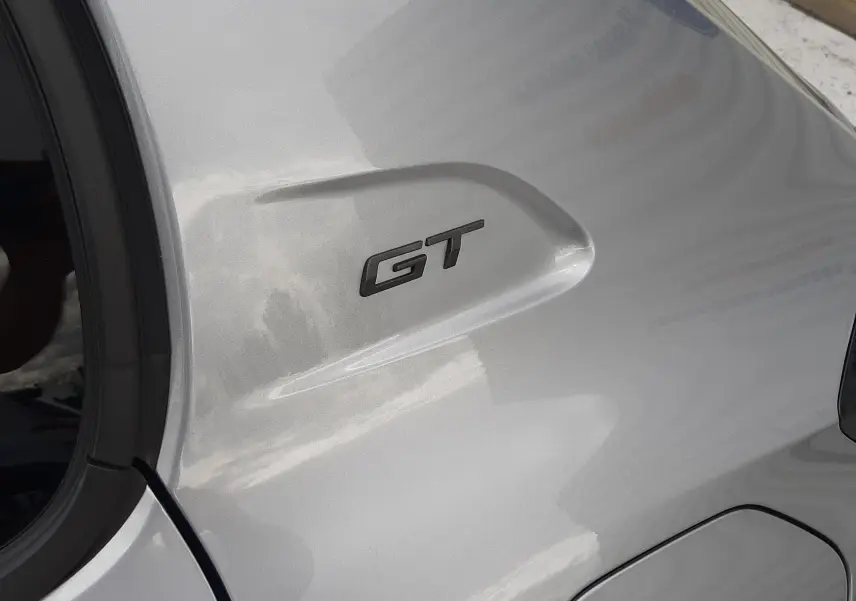 Détail de l'aile arrière droite gris Artense d'une Peugeot 208 GT avec logo GT en relief.