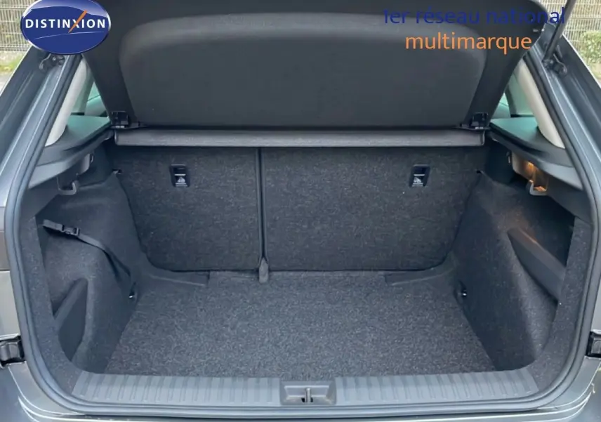 Coffre ouvert vu de l’arrière d’un Skoda Kamiq gris graphite métal, montrant un espace de chargement propre et vide.