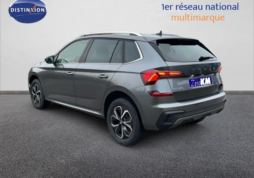 Vue 3/4 arrière droite du Skoda Kamiq gris graphite métal avec feux arrière allumés sur fond neutre.