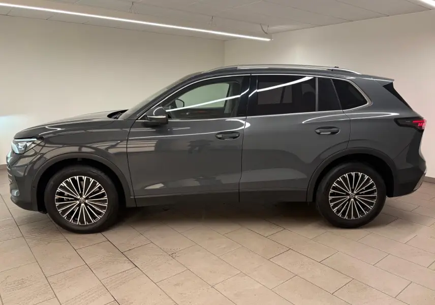 Vue de profil côté gauche du Volkswagen Tiguan 2.0 TDI 150 DSG7 Elegance 2025 en gris dauphin métallisé, roues alliage distinctives.