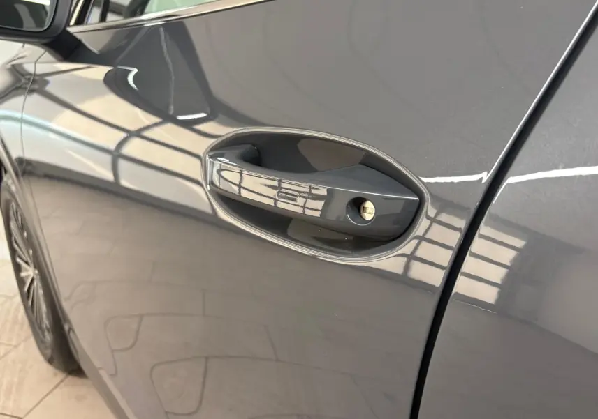 Poignée de porte côté gauche en gros plan sur Volkswagen Tiguan 2025 gris dauphin métallisé, reflet lumineux sur la carrosserie.