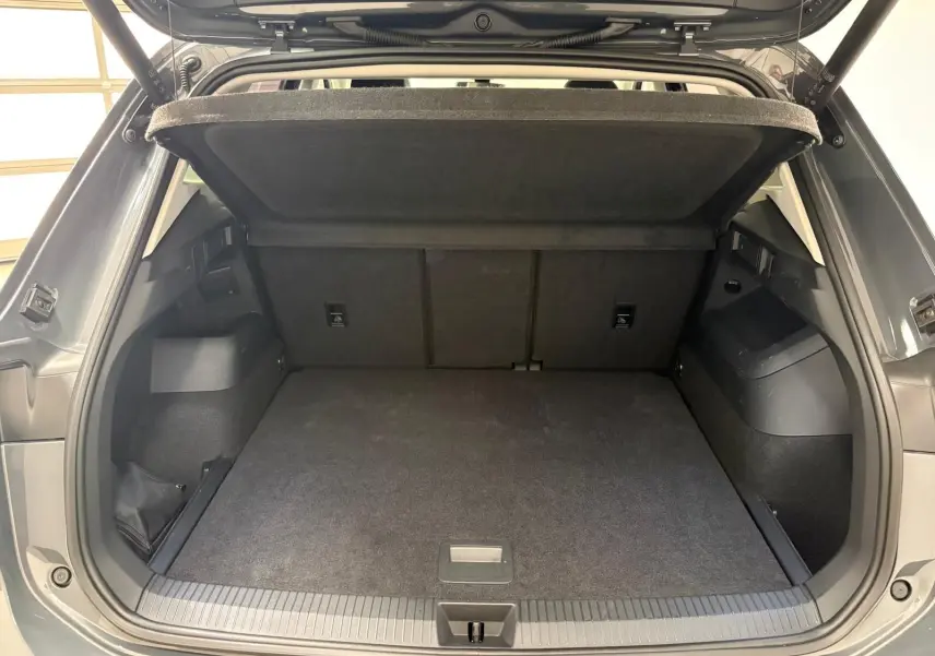Vue arrière du coffre ouvert du Volkswagen Tiguan 2.0 TDI Gris Dauphin, montrant l'espace de chargement et la tablette cache-bagages.