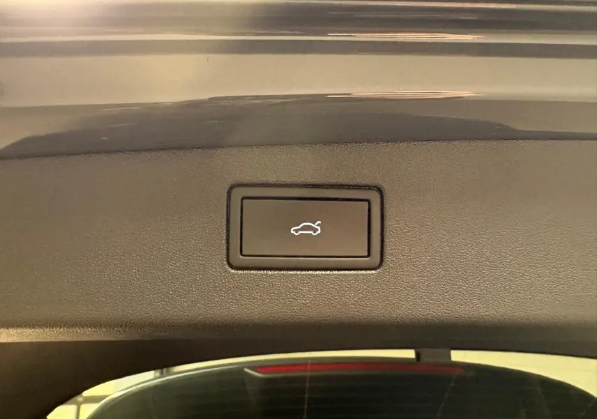 Bouton d'ouverture électrique du coffre sur le hayon d'un Volkswagen Tiguan gris dauphin, vue intérieure rapprochée.