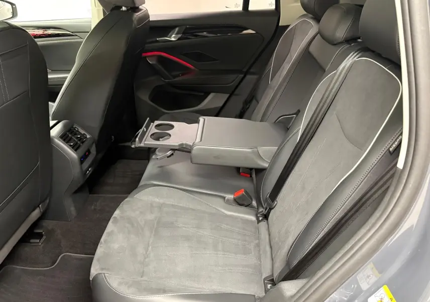 Vue intérieure côté droit des sièges arrière gris clair du Volkswagen Tiguan 2025 avec accoudoir central et porte-gobelets déployés.