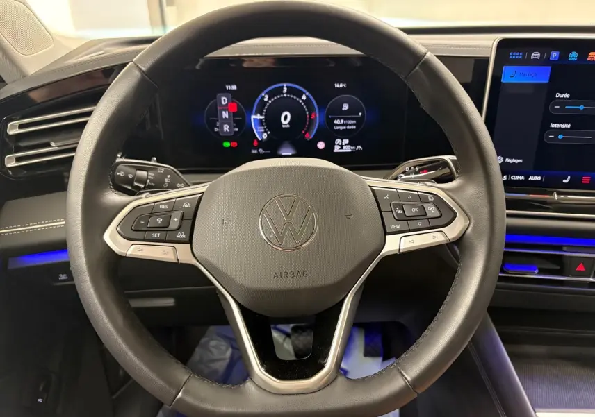 Vue centrée sur le volant noir du Volkswagen Tiguan 2.0 TDI 150 DSG7 avec tableau de bord numérique allumé.