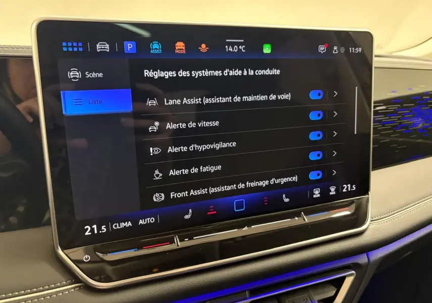 Écran tactile central du Volkswagen Tiguan 2025 affichant les réglages des aides à la conduite, avec tableau de bord beige et éclairage bleu.