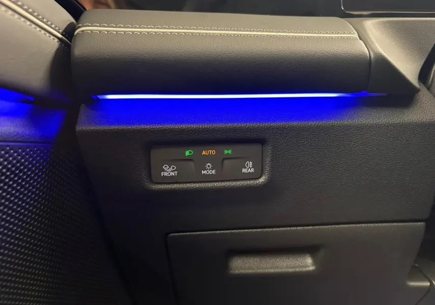 Détail intérieur côté gauche du Volkswagen Tiguan 2.0 TDI 150 DSG7 Elegance avec éclairage d'ambiance bleu et commandes des phares.