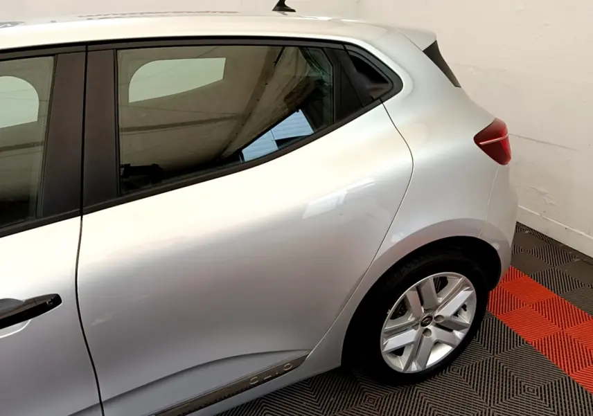 Vue latérale arrière droite d'une Renault Clio Business TCe 100 gris clair avec jante alliage et poignées de porte noires.
