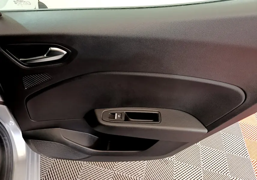 Vue rapprochée de la porte avant gauche noire de la Renault Clio Business TCe 100 gris clair, avec poignée et bouton de lève-vitre.