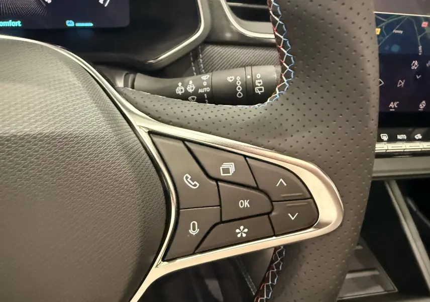 Gros plan sur les commandes multifonctions à droite du volant perforé noir du Renault Captur E-Tech blanc nacré 2026.