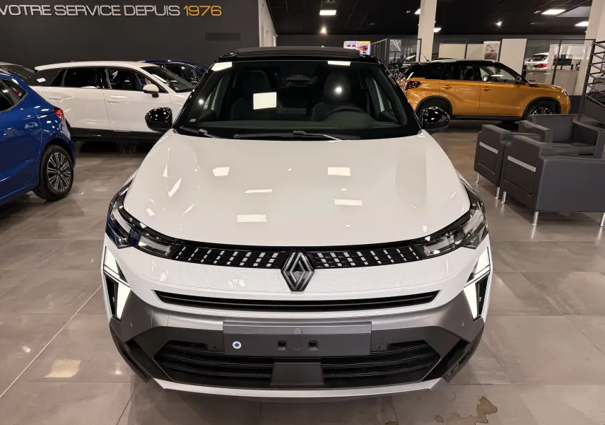Vue avant d’un Renault Captur E-Tech blanc nacré avec toit noir, éclairage LED distinctif en concession.