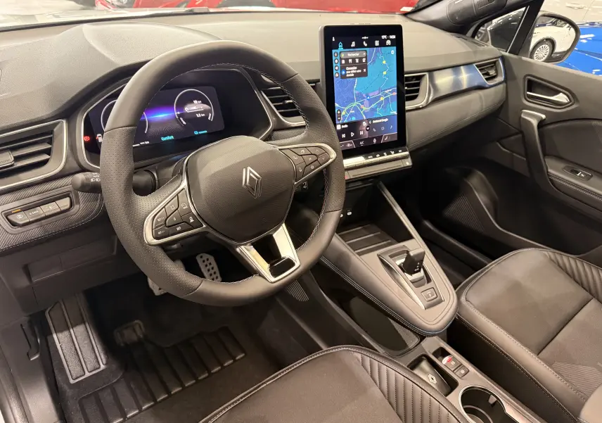 Vue intérieure côté conducteur du Renault Captur E-Tech 2026, volant multifonction, écran tactile vertical et sellerie noire.